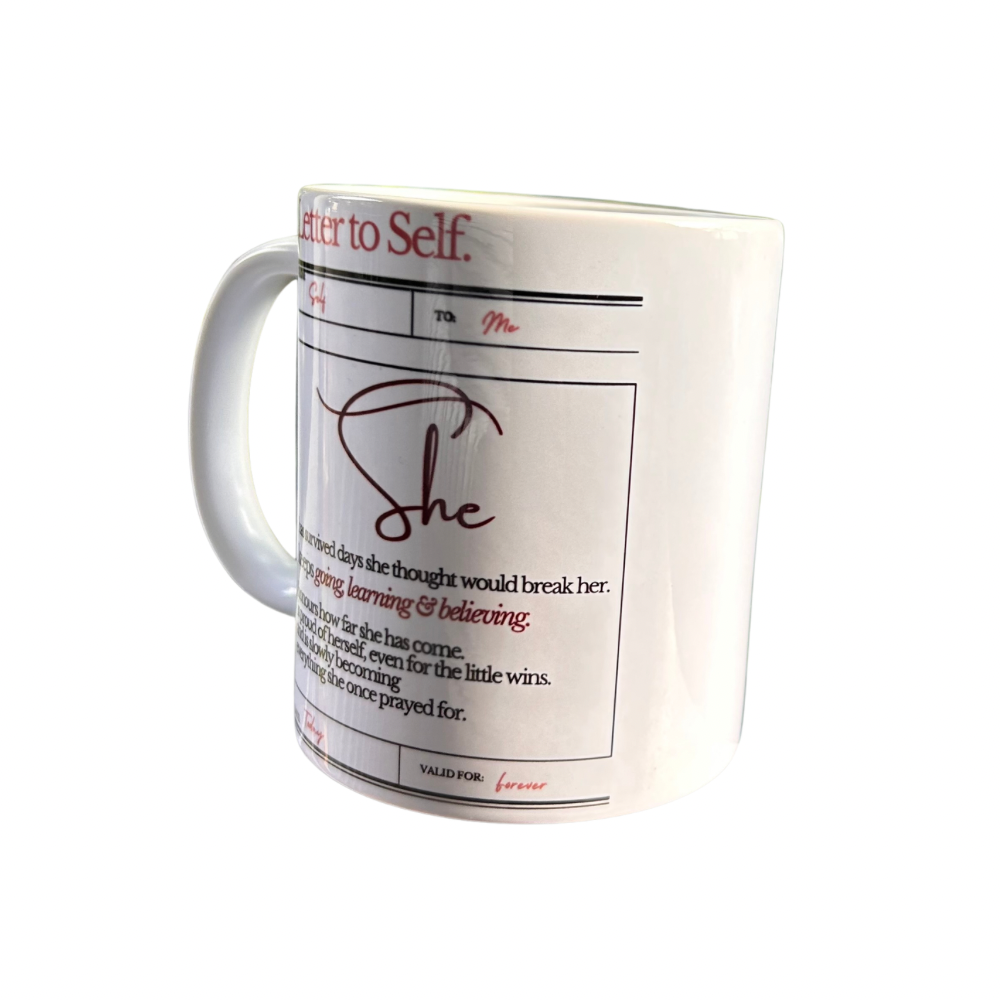 A white ceramic coffee mug featuring a 'Letter to Self' format design with a cursive 'She' and inspirational text printed in black and red.